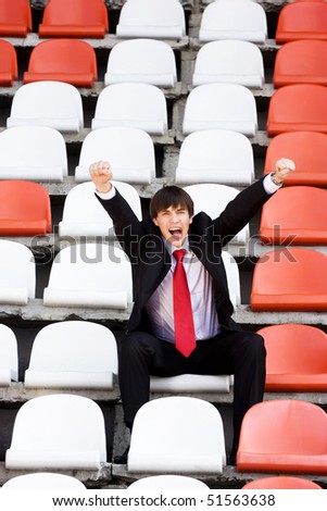 young man in black suit sitting on the audience bleachers