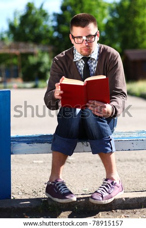 Man nerd in glasses with red book outdoor