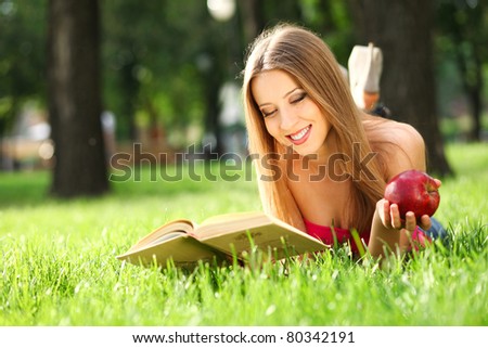 Woman reading book in the park on the grass