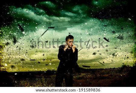 Handsome young man  in business suit standing in the middle of the field during a storm. Green sky background