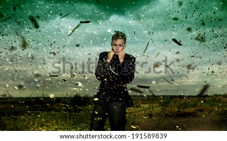 Handsome young man  in business suit standing in the middle of the field during a storm. Dark green sky background