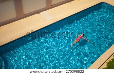 Beauty Woman In Red Swimming Suit Swimming and Relaxing In Big Blue \
Pool. Top view.