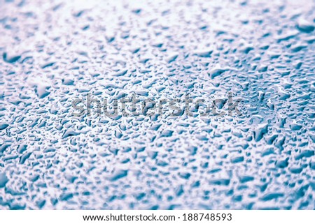Water drops on metal background with reflection blurred on the edges. Image processing with blue color filter effect
