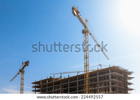 Industrial crane and building construction site against the sun and blue sky