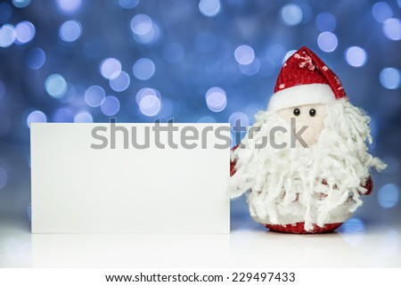 Santa Claus or Father Frost with greeting white blank card on Christmas lights background on white surface