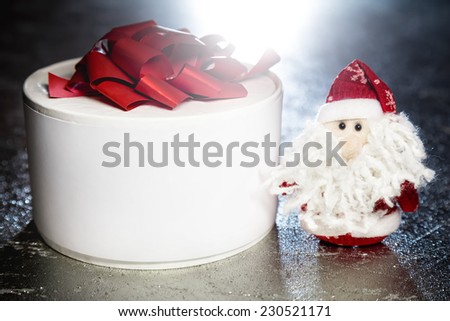 Christmas Santa Claus or Father Frost and white gift box or present on silver or metal grunge surface with back light from behind
