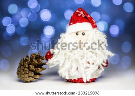 Santa Claus or Father Frost and pine cone with Christmas lights at background on white surface
