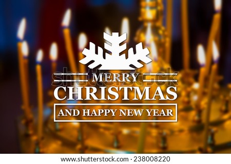 Merry Christmas and New Year greeting card on blurred glowing yellow church candles on background