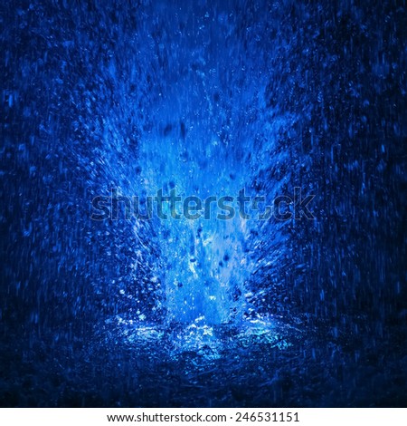 Abstract colorful fountain splashes blue color of water drops on a black background. motion blur