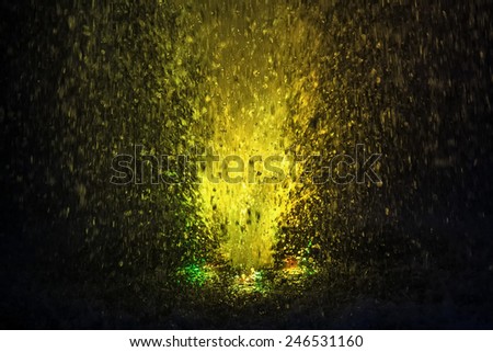 Abstract colorful fountain splashes yellow color of water drops on a black background. motion blur