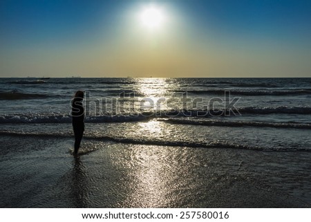 Scenic view from beach in Goa to beautiful sunrise above the Arabian sea. Silhouette of woman or girl looks at sea