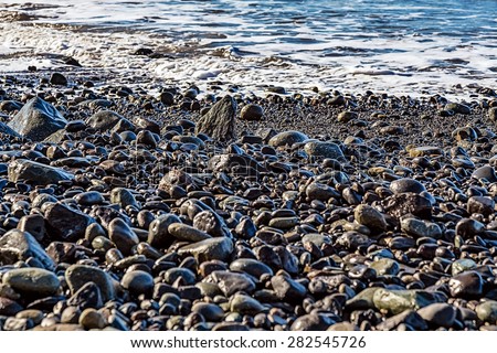 Stones and water with waves on the beach coast or shore of ocean or sea