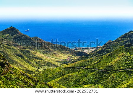 Coast or shore of Atlantic ocean with green mountain or rock and sky with skyline or horizon in Tenerife Canary island, Spain at spring or summer