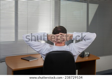 A relaxed business man kepping hands behind head