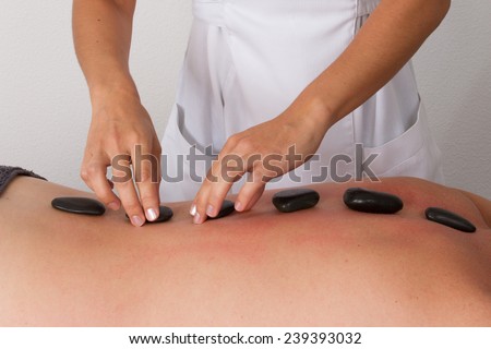 a man is lying on massage table, black hot stones therapy