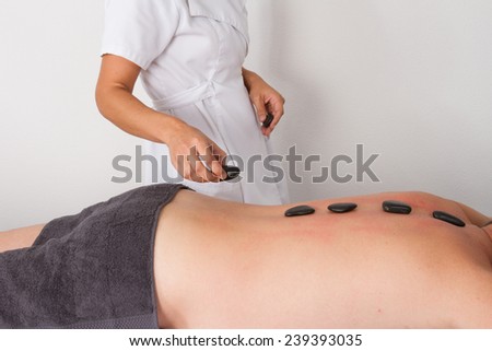 a man is lying on massage table, black hot stones therapy