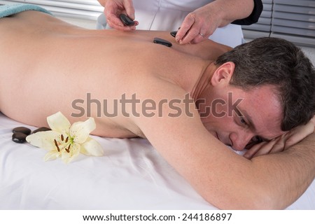 Image of hand placing Lastone on man\'s back in spa