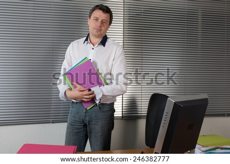 Happy businessman standing behind office desk, annoyed