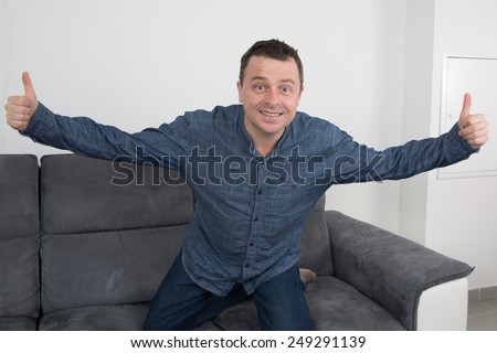 Man lying on sofa with arms in the air