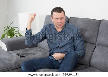 Happy Man lying on sofa with his fist  in the air