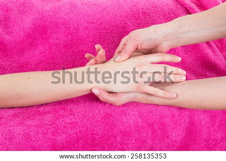 A woman is getting a hand massage on pink towel
