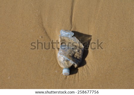 A blue plastic bottle littering a beach - pollution