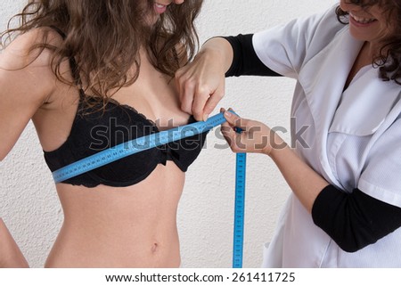 Slim woman measuring waist with tape measure in centimeters