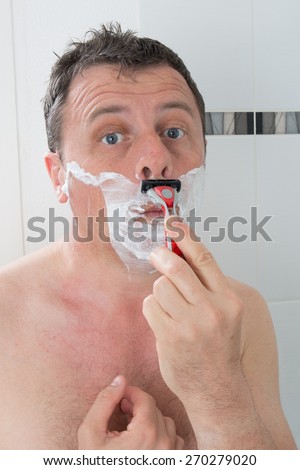 Man shaving with a razor blade and shaving cream