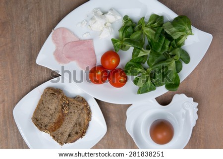 Tomato salad and heart shaped ham on wooden table