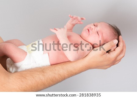 New born baby is held by his father isolated on grey