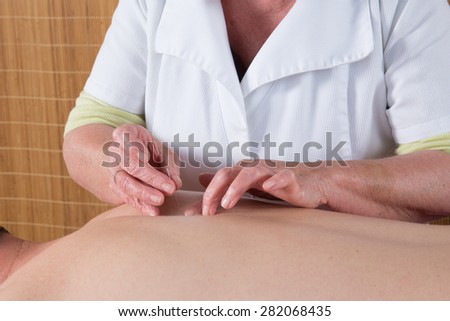 Acupuncturist prepares to tap needle around face of man