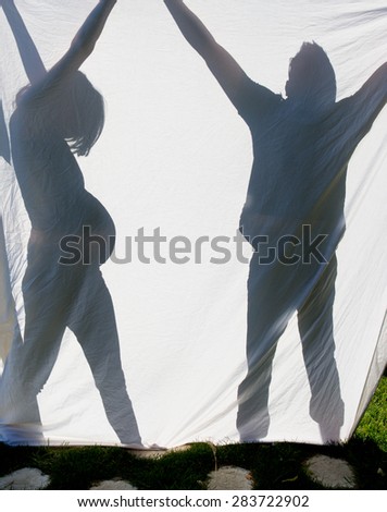 Shadows of a couple expecting a baby behind a sheet