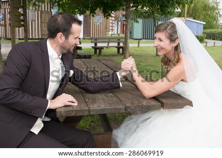 Young happy newly wed couple  fighting in arm wrestling