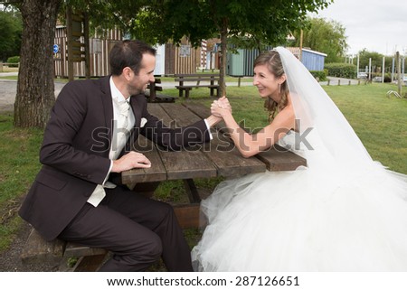 Young happy newly wed couple  fighting in arm wrestling