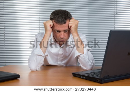 Worried businessman holding his head in his office