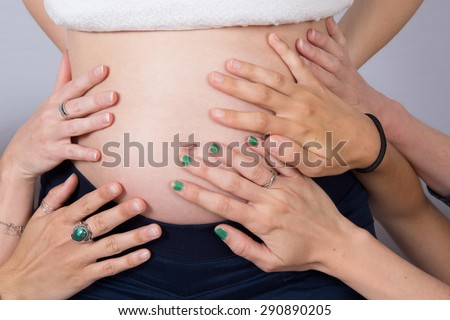 Woman\'s hands on pregnant woman stomach. indoor shot