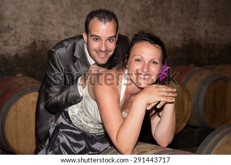 Newlywed couple in the wine cellar after their wedding looking at the camera