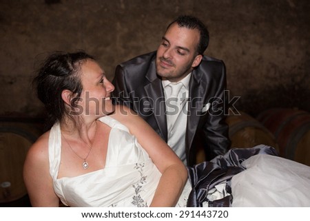 A bride and groom  in the wine cellar after their wedding looking at the camera