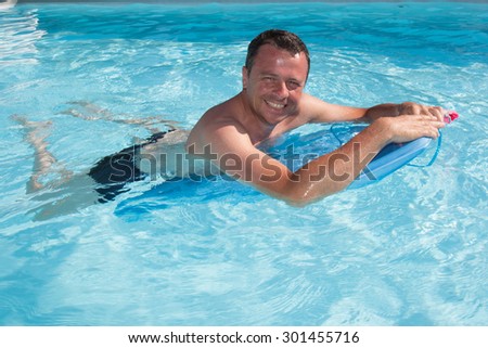 Surfer man swim with his surf board in blue water swimming  and smile