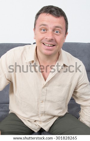 Portrait of a happy and   relaxed man sitting on sofa in the house