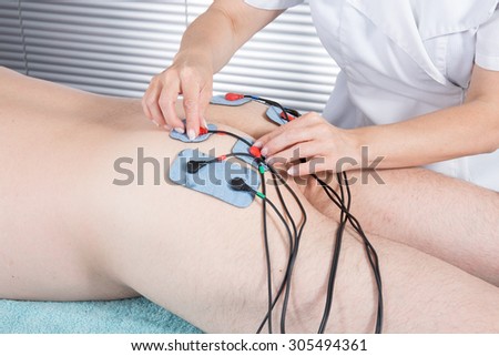 Man getting electric massage for leg muscles in spa