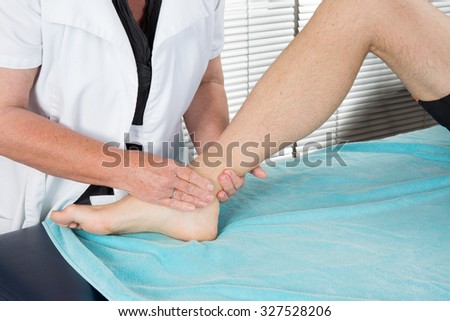 Physiotherapist controlling leg of a patient in bright office