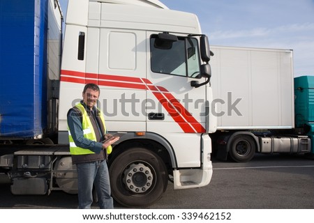 Logistics - proud driver or forwarder in drivers cap of truck and trailer, on a transshipment point