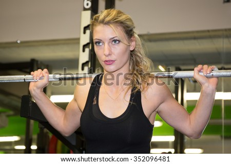 Bodybuilding. Strong fit woman exercising with dumbbells. Muscular blonde girl lifting weights studio shot on dark