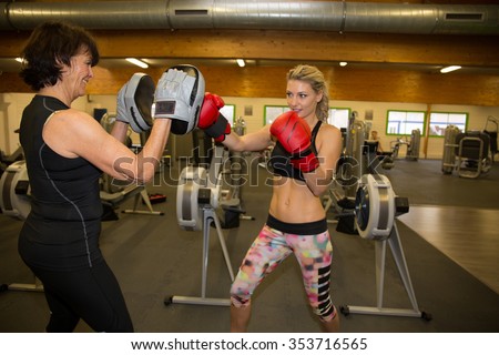 Two women boxing together at a gym center