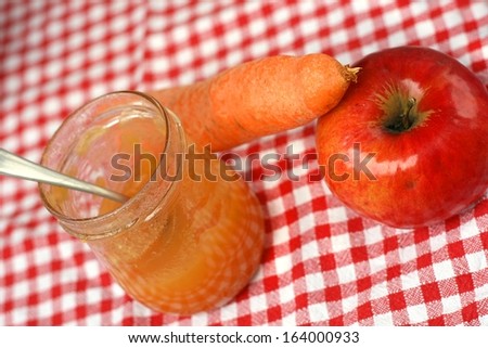 Carrot and apple jam on red checked fabric tablecloth with small spoon