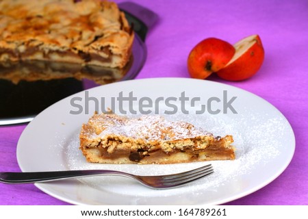 Home made just baked apple pie with raisins on white plate with powdered (icing) sugar