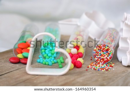 Sweet bright colored candy for children's cookies and cake decoration on wooden table with plastic white cookie cutters