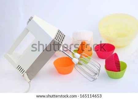 Retro electric hand mixer (eggbeater) with two beaters, Variety of cupcake liners and bowl in different colors in background