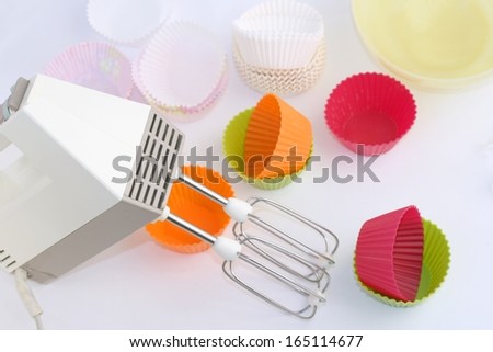 Retro electric hand mixer (eggbeater) with two beaters, Variety of cupcake liners and bowl in different colors in background
